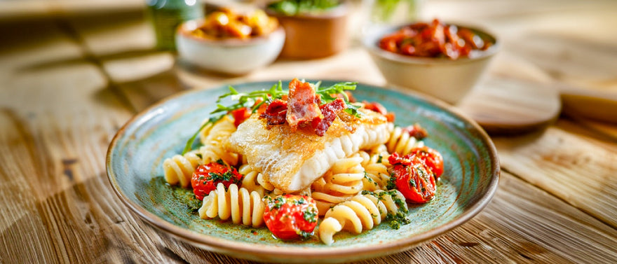 Gebratener Zander auf Spiralnudeln in Knoblauch-Kräuteröl mit Schmortomaten und Pancetta