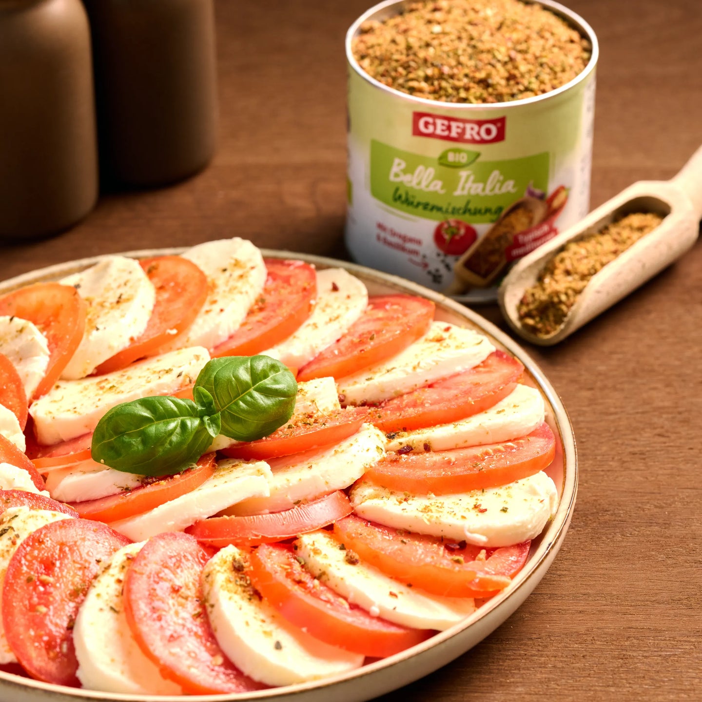 Caprese-Salat mit Tomaten, Mozzarella und Basilikum auf einem Teller, daneben italienische Gewürzmischung von Gefro