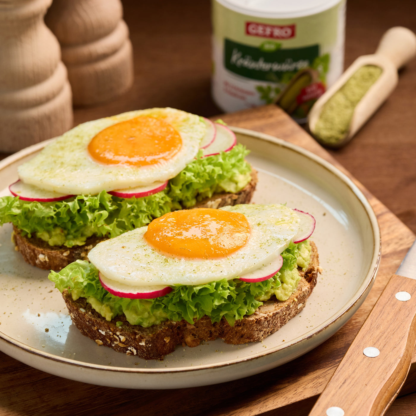 Zwei belegte Brote mit Salat, Radieschen, Avocado und Spiegelei auf einem Teller, appetitlich angerichtet