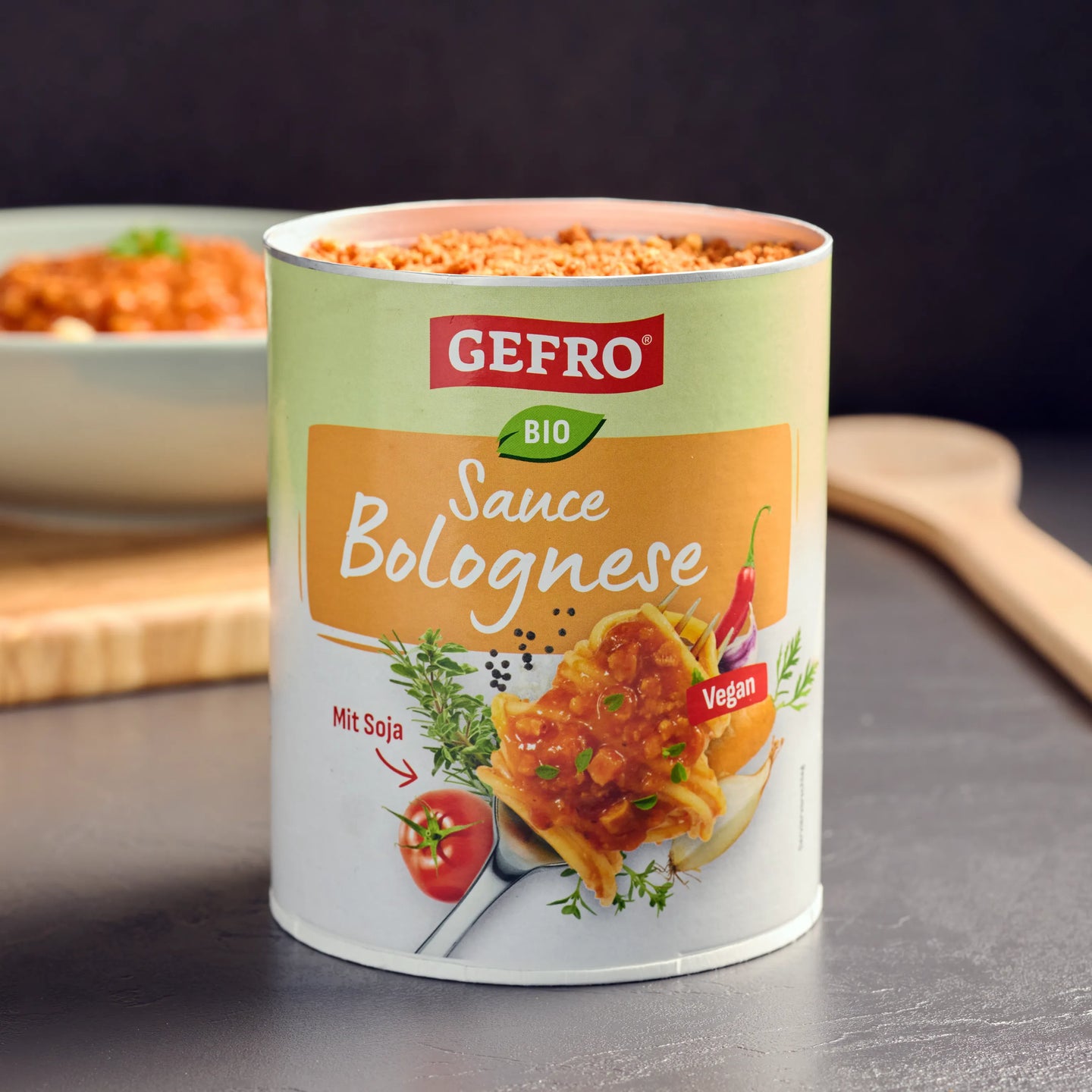 Dose GEFRO Bio Sauce Bolognese mit Soja, vegan, geöffnet auf Tisch vor unscharfer Schüssel mit Pasta im Hintergrund