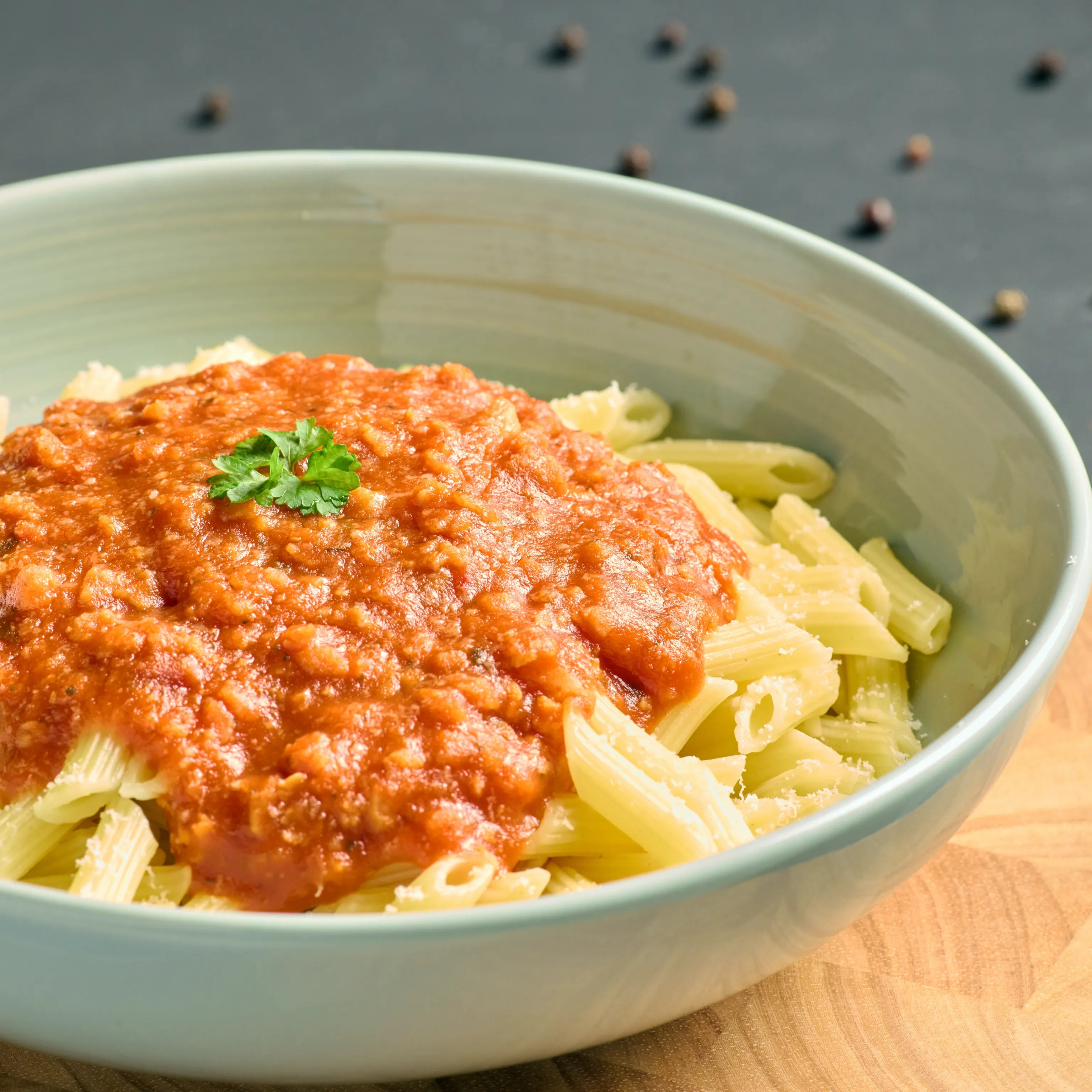 Schüssel mit Penne und kräftiger Tomatensauce, garniert mit Petersilie, als warmes Pastagericht serviert