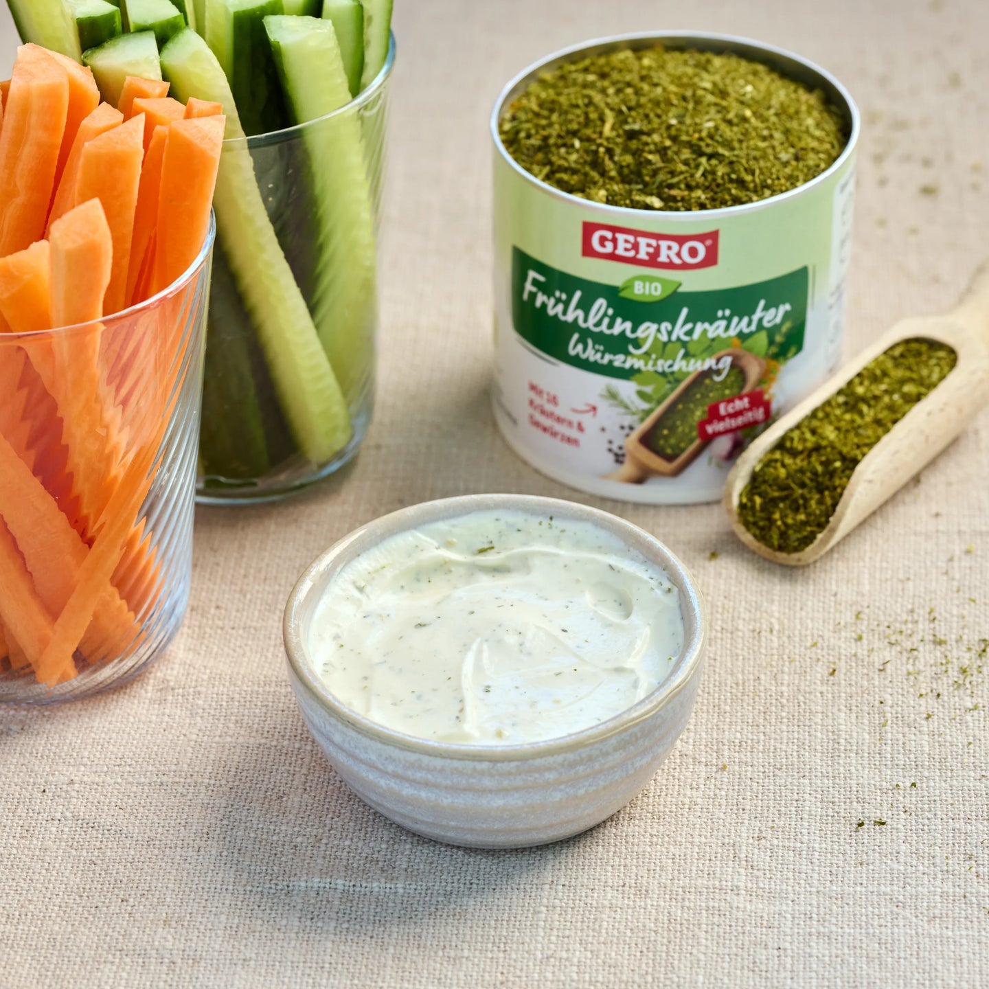 Kräuterdip in Schale mit Karotten- und Gurkensticks, daneben Bio-Frühlingskräuter-Würzmischung von Gefro
