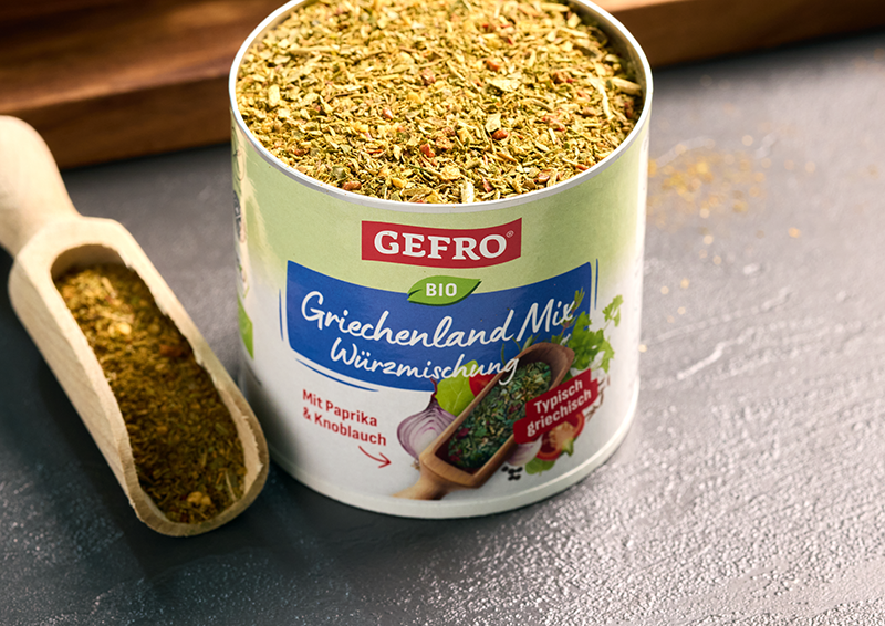 Dose mit GEFRO Bio Griechenland-Mix Würzmischung, offen gefüllt, daneben eine Holzschaufel mit Gewürz
