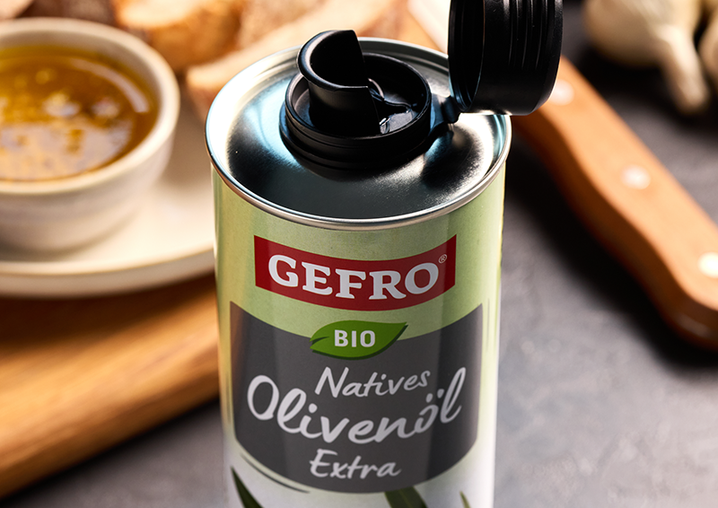 Geöffnete Dose GEFRO Bio natives Olivenöl extra mit Ausgießer, daneben Brot und eine Schale mit Öl.