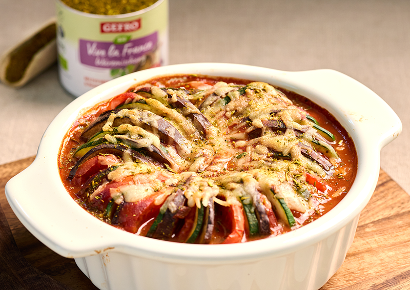 Weißer Auflauf mit Tomaten, Zucchini und roten Zwiebeln in Tomatensoße, mit Käse überbacken und servierfertig
