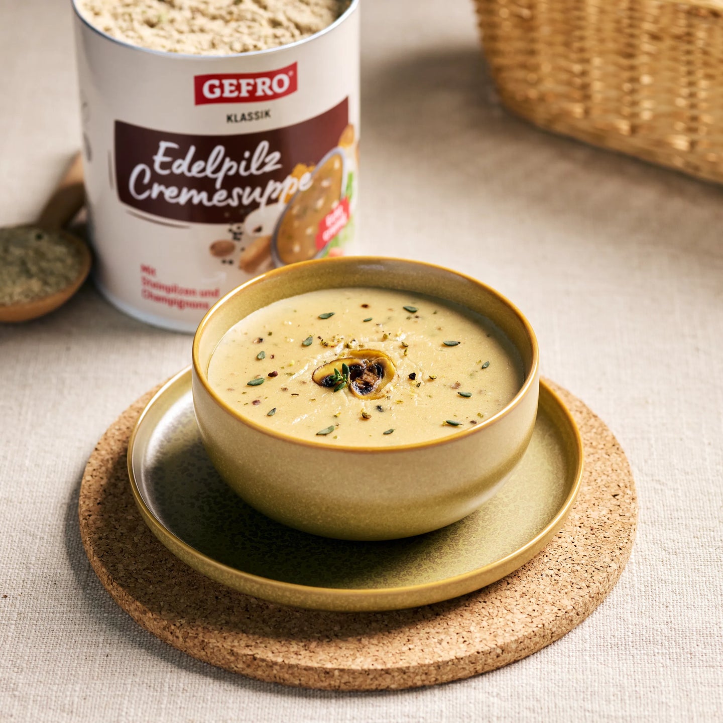 Schale mit cremiger Edelpilz-Cremesuppe, garniert mit Pilzscheibe und Kräutern, daneben GEFRO Produktdose】【。
