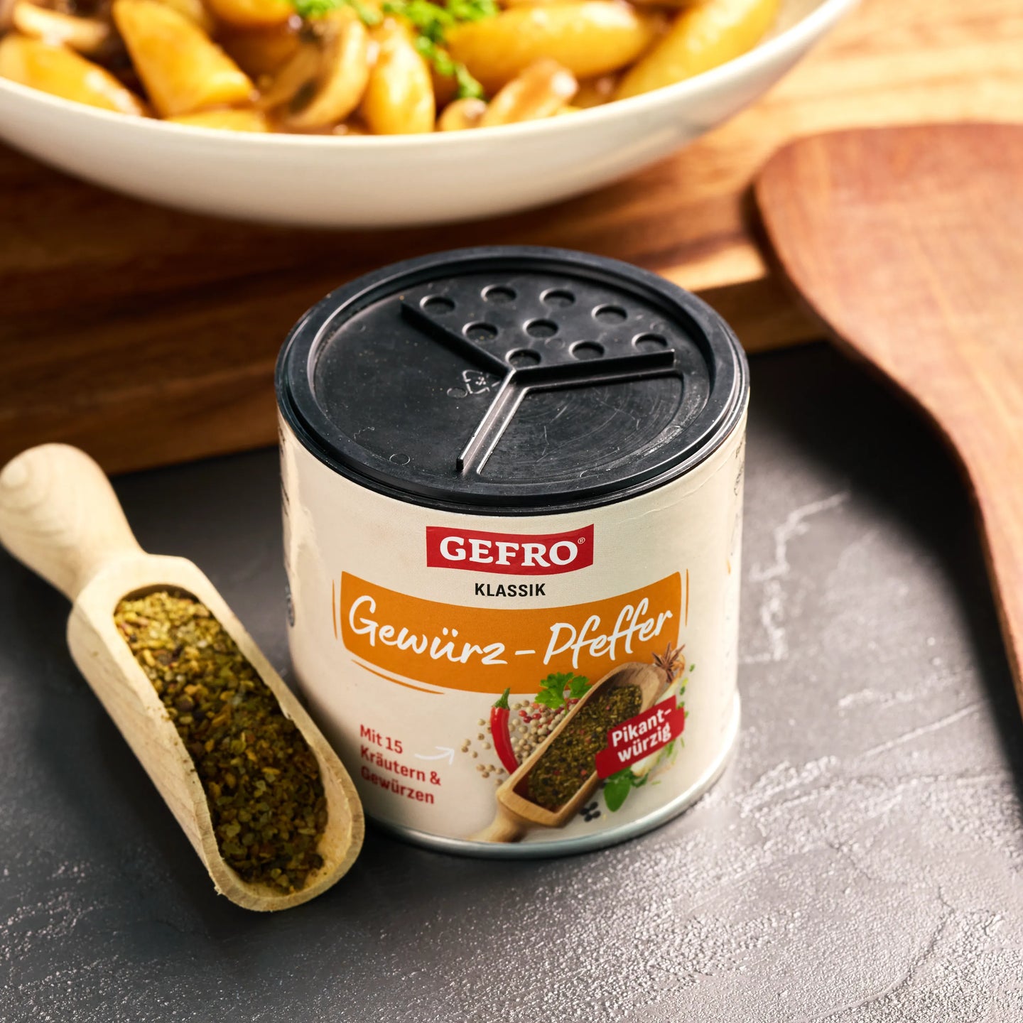 GEFRO Klassik Gewürz-Pfeffer in Dose mit Streuerdeckel, daneben eine Holzschaufel mit Gewürzmischung.