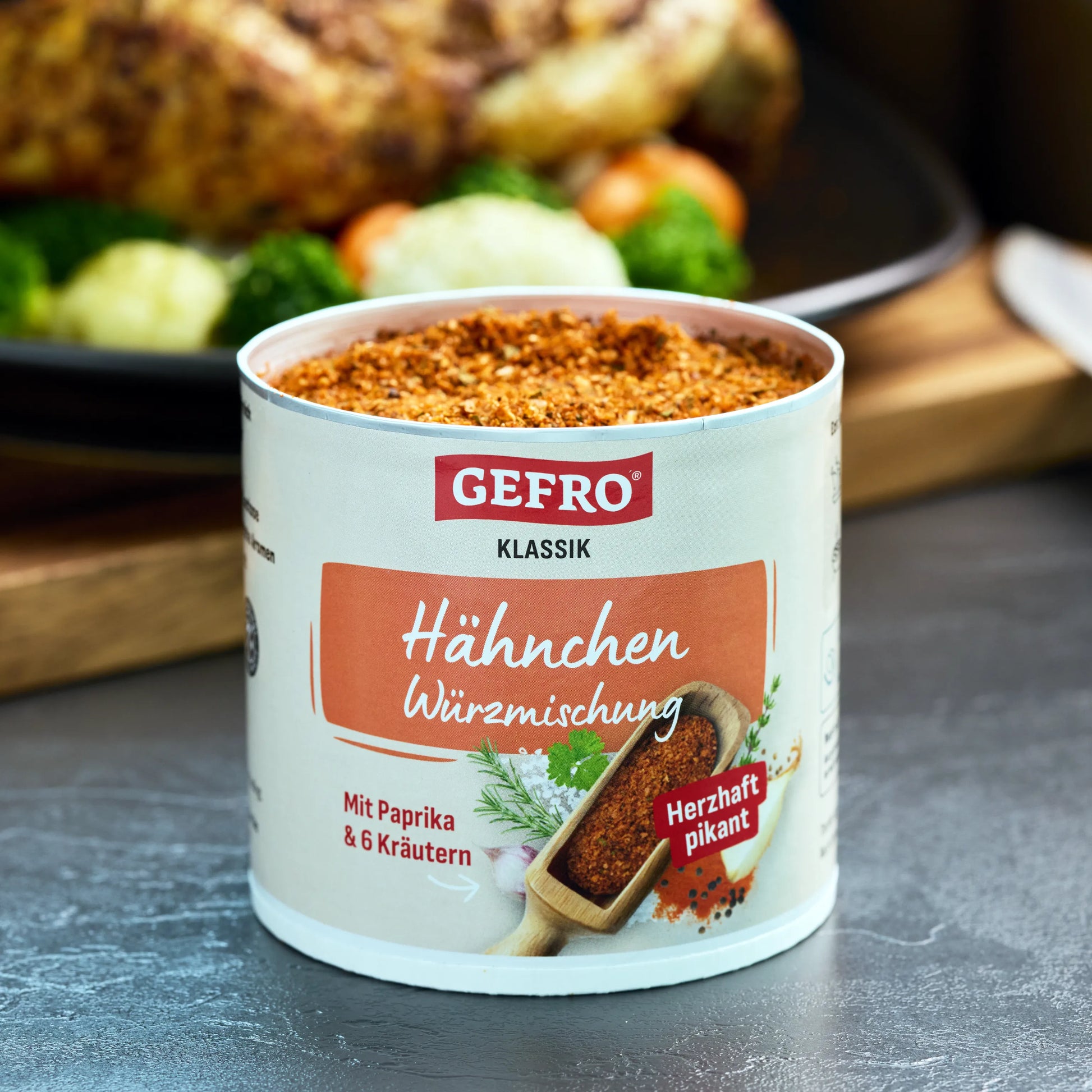 Dose GEFRO Klassik Hähnchen Würzmischung, geöffnet und gefüllt, vor gebratenem Hähnchen mit Gemüse platziert