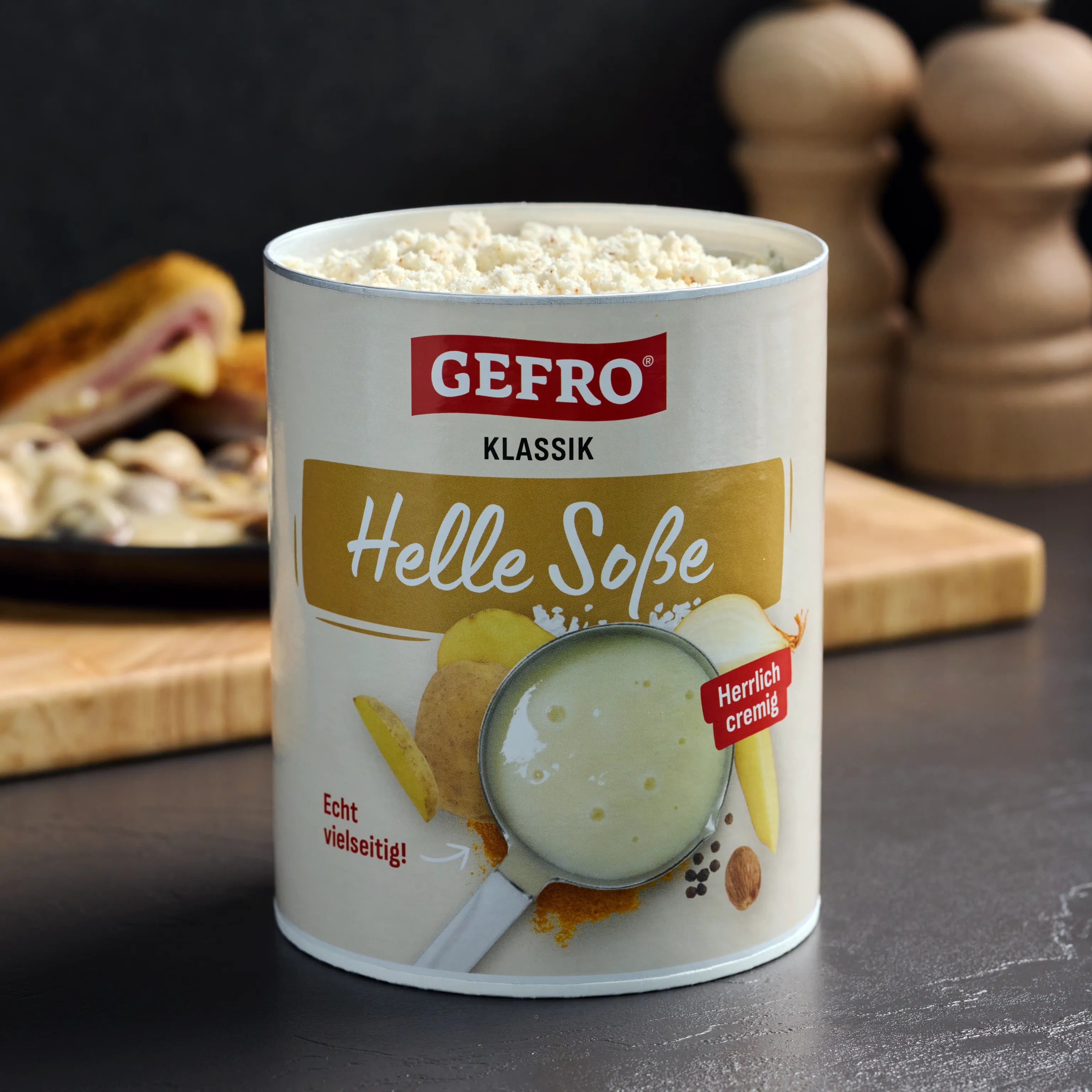 Dose GEFRO Klassik Helle Soße mit Pulverfüllung auf dunklem Tisch, davor Produktverpackung für helle Soße sichtbar