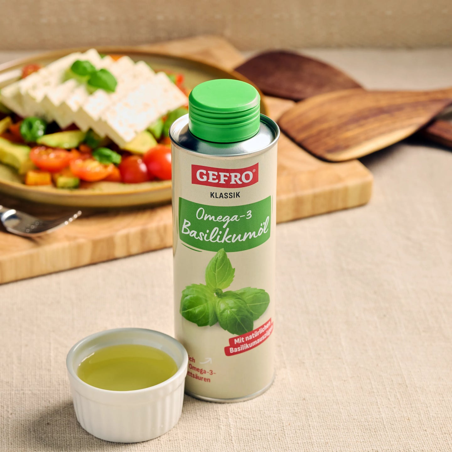 GEFRO Klassik Omega-3 Basilikumöl in Dose mit grünem Deckel, davor eine Schale Öl, im Hintergrund ein Salat.