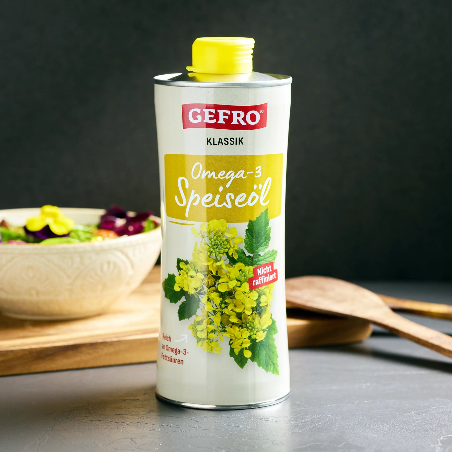 Gefro Klassik Omega-3 Speiseöl in Metallflasche mit gelbem Deckel, daneben Salatschüssel und Holzlöffel.