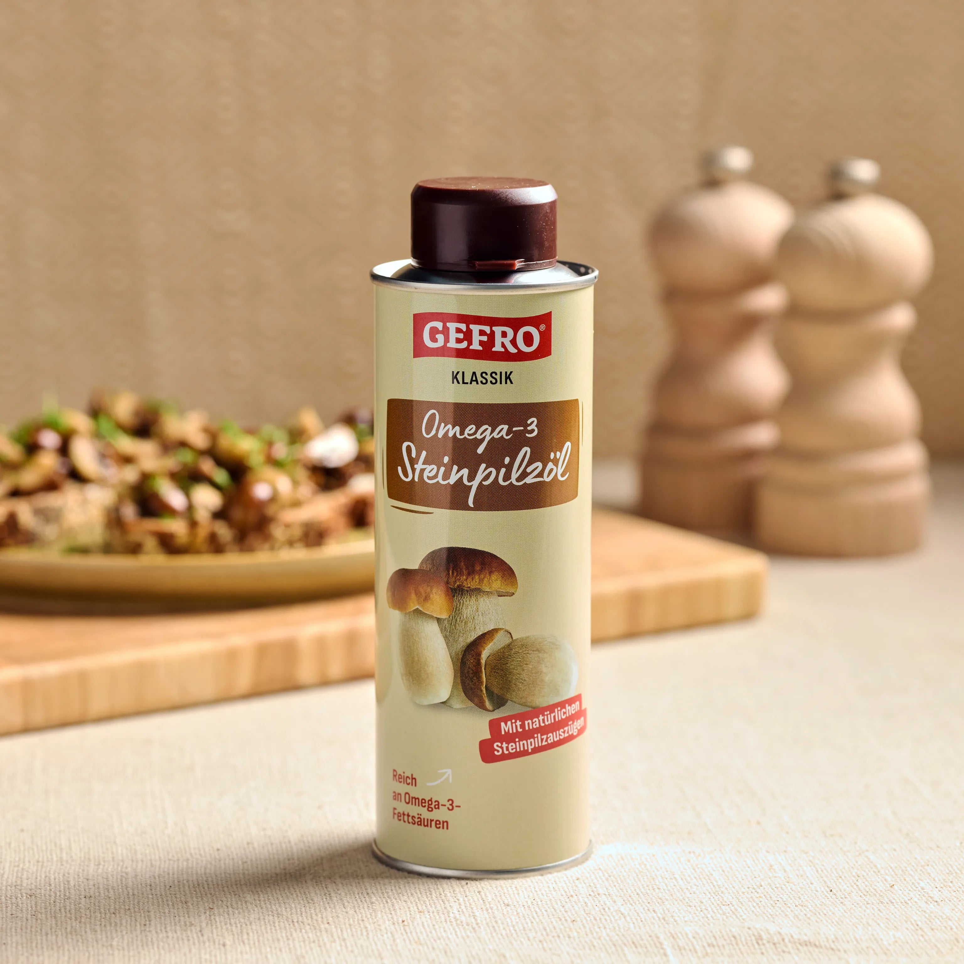 Dose GEFRO Klassik Omega-3 Steinpilzöl auf Tisch, im Hintergrund Gericht und Gewürzmühlen in der Küche