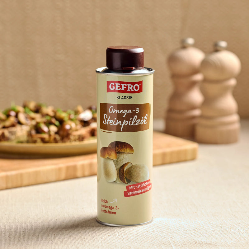 Dose GEFRO Klassik Omega-3 Steinpilzöl auf Tisch, im Hintergrund Gericht und Gewürzmühlen in der Küche