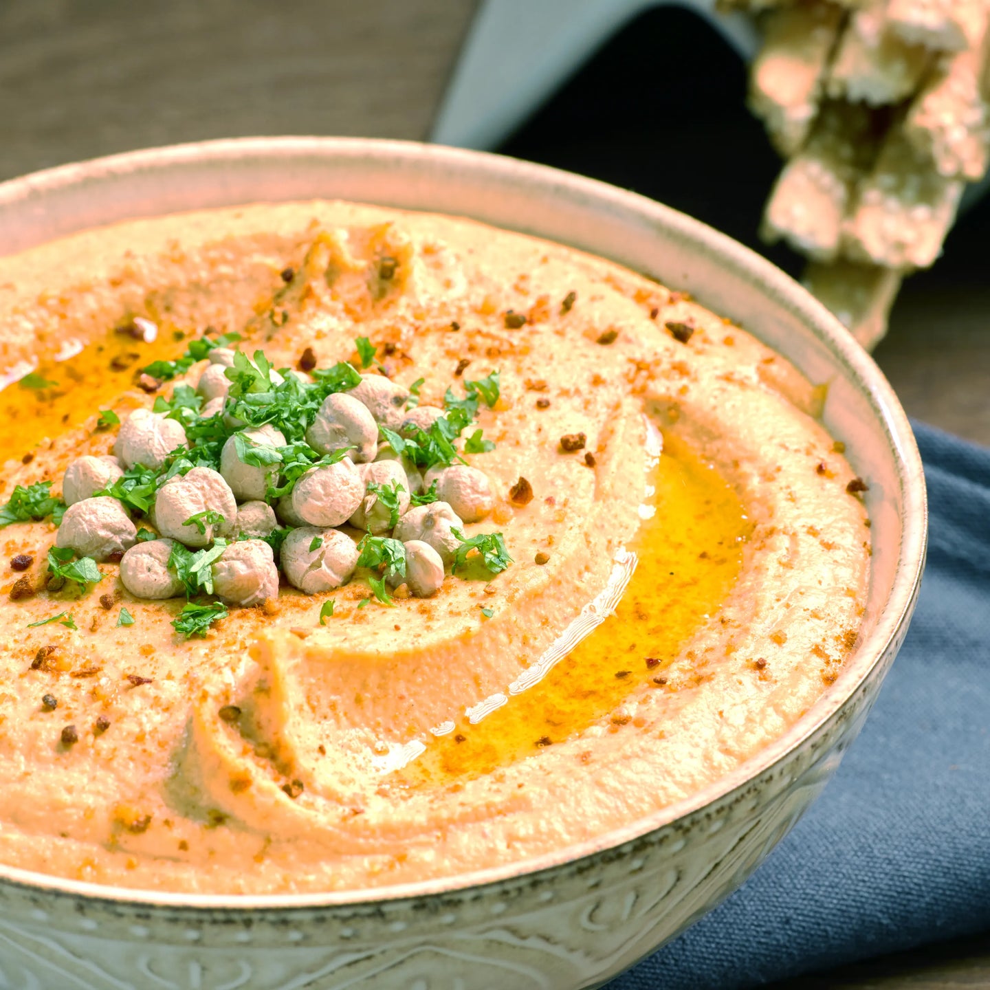 Schale mit cremigem Hummus, garniert mit Kichererbsen, Petersilie, Öl und Gewürzen, servierfertig auf dem Tisch