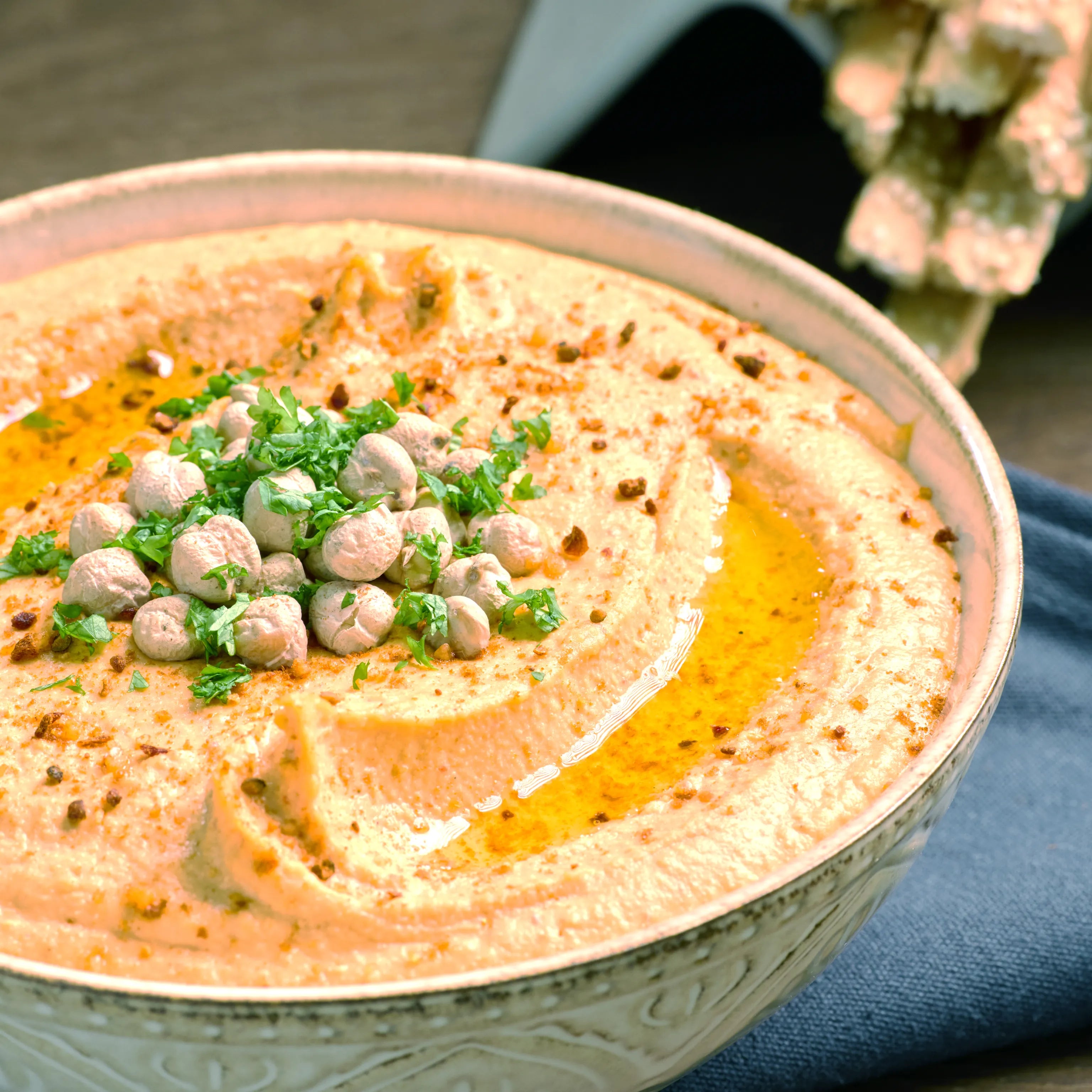 Schale mit cremigem Hummus, garniert mit Kichererbsen, Petersilie, Öl und Gewürzen, servierfertig auf dem Tisch