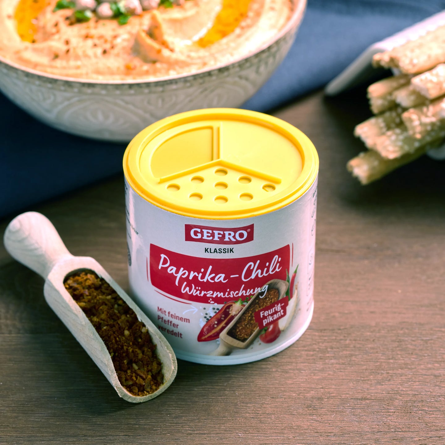 Dose GEFRO Paprika-Chili Würzmischung mit Streuverschluss, daneben Holzschaufel mit Gewürz auf dem Tisch