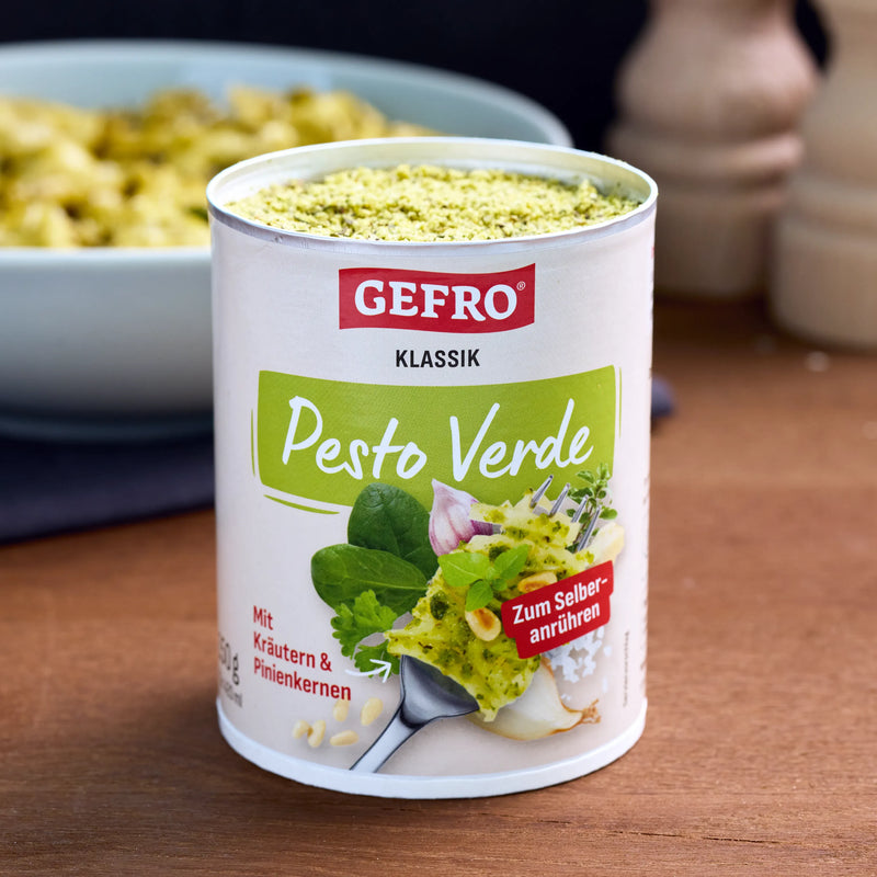 Dose GEFRO Klassik Pesto Verde zum Selberanrühren auf Holztisch, mit grünem Pulver und unscharfer Schüssel im Hintergrund