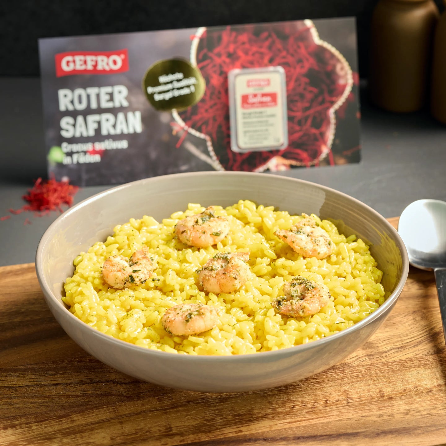 Schale mit gelbem Safranreis und Garnelen, dahinter GEFRO Roter Safran als Gewürz in Fäden präsentiert.