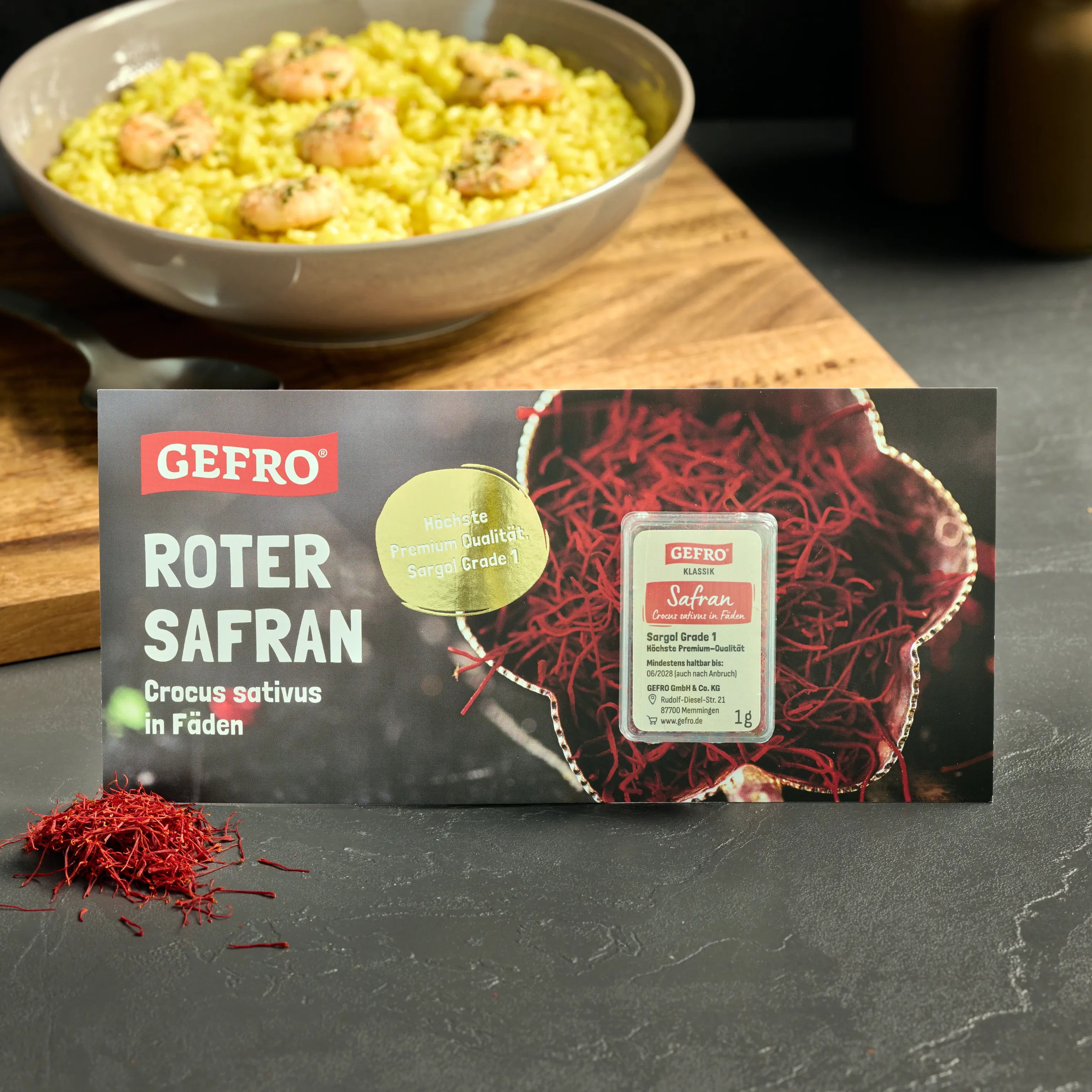 GEFRO Roter Safran in Fäden, 1 g Packung vor Safranfäden und gelbem Reisgericht mit Garnelen im Hintergrund