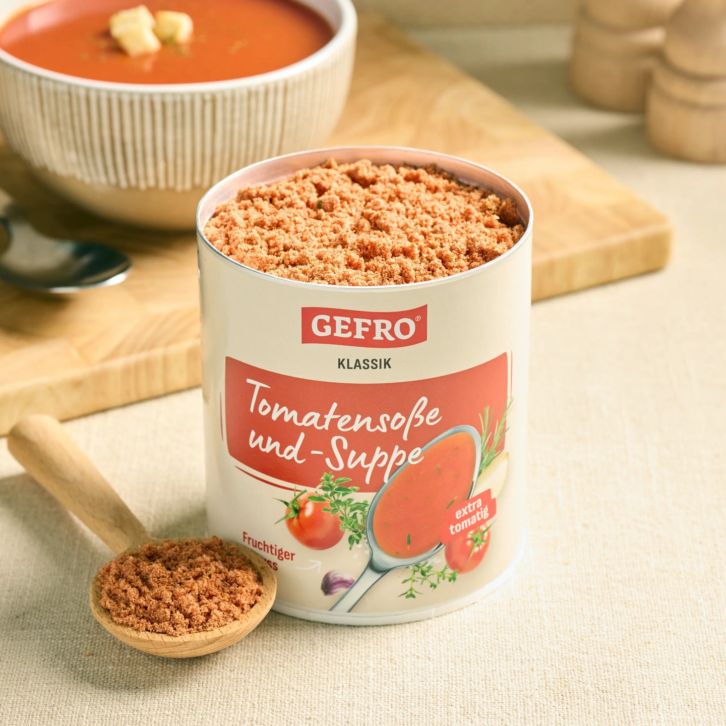 Dose GEFRO Klassik Tomatensoße und -Suppe mit Pulver auf Löffel, daneben servierfertige Tomatensuppe in Schale