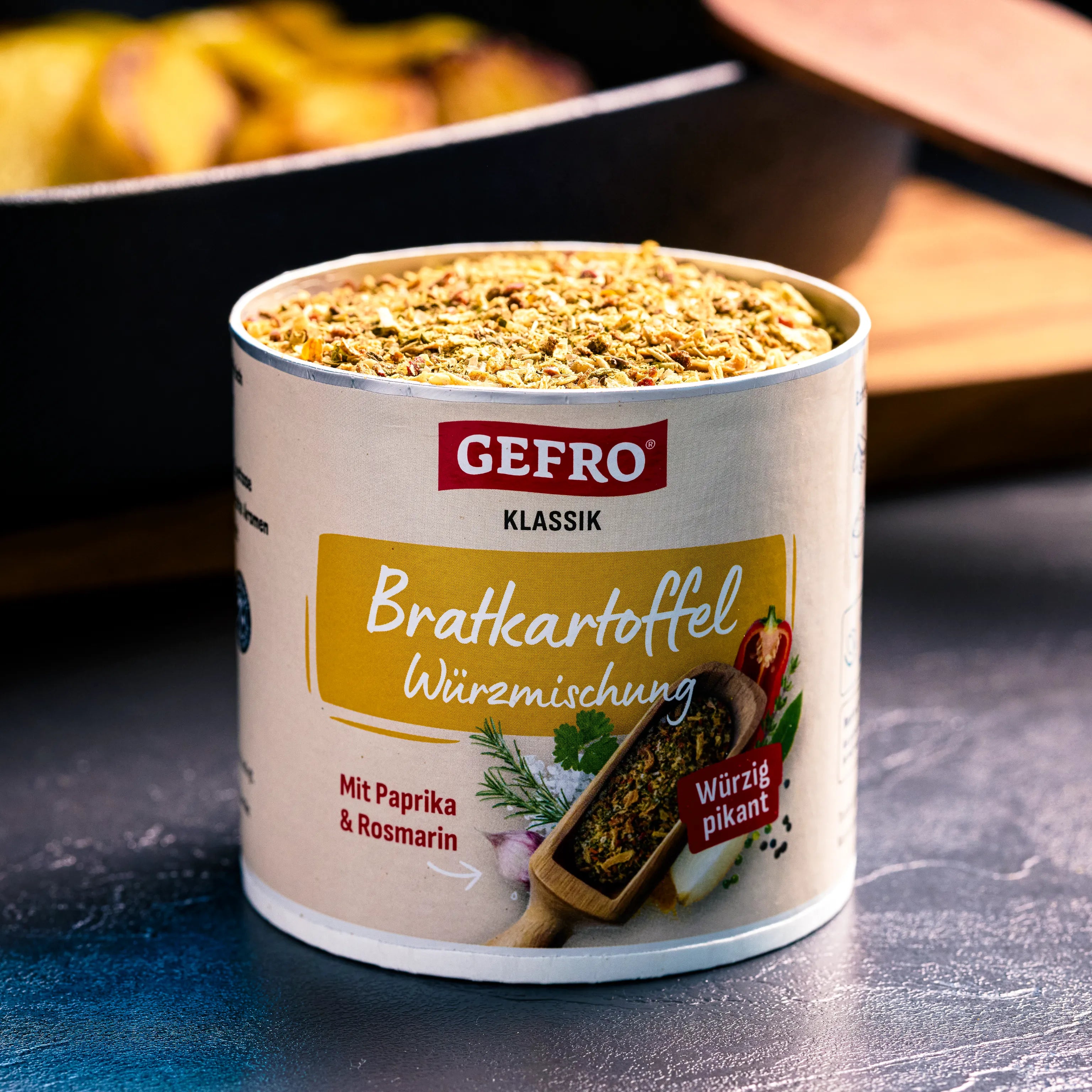 Dose GEFRO Klassik Bratkartoffel-Würzmischung mit Paprika und Rosmarin, geöffnet vor Pfanne mit Kartoffeln