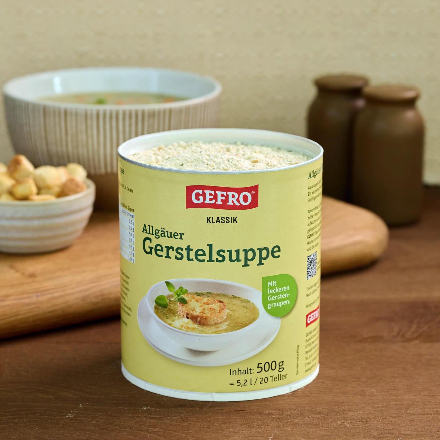Dose GEFRO Klassik Allgäuer Gerstelsuppe mit 500 g Inhalt auf Holztisch, daneben eine Schüssel mit Suppe.