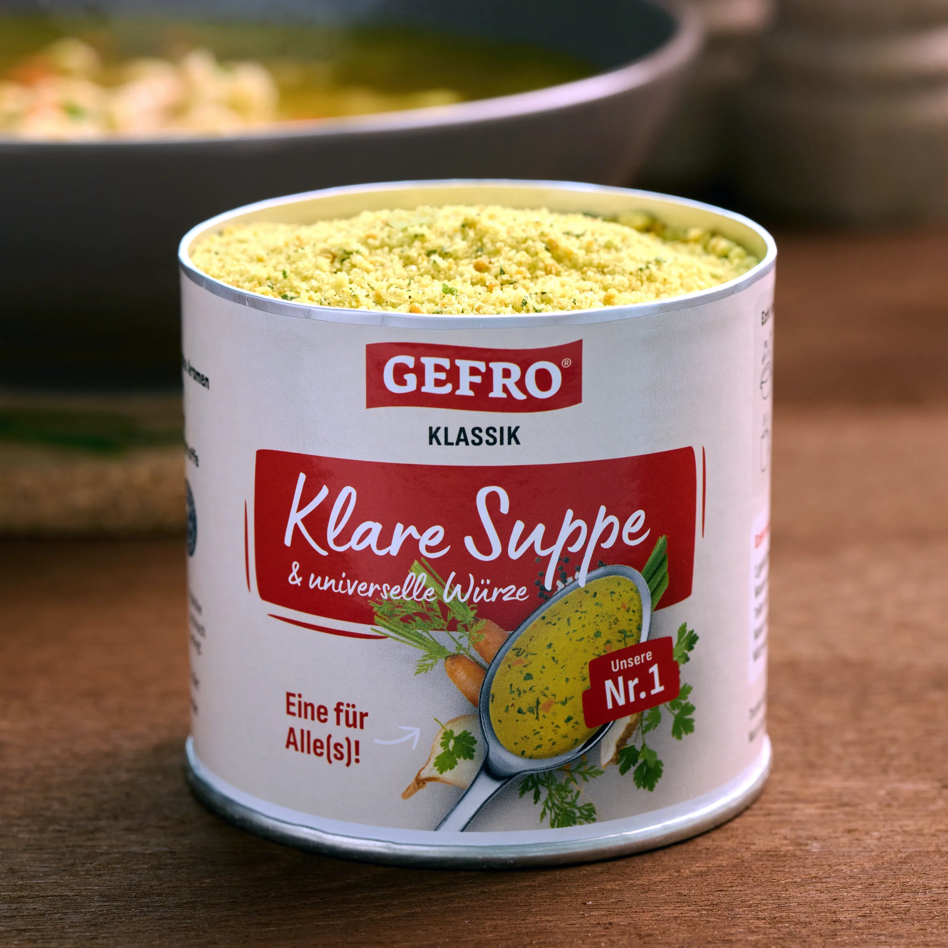 Dose mit GEFRO Klare Suppe Klassik, geöffnet und mit Suppenpulver gefüllt, auf einem Holztisch in der Küche.