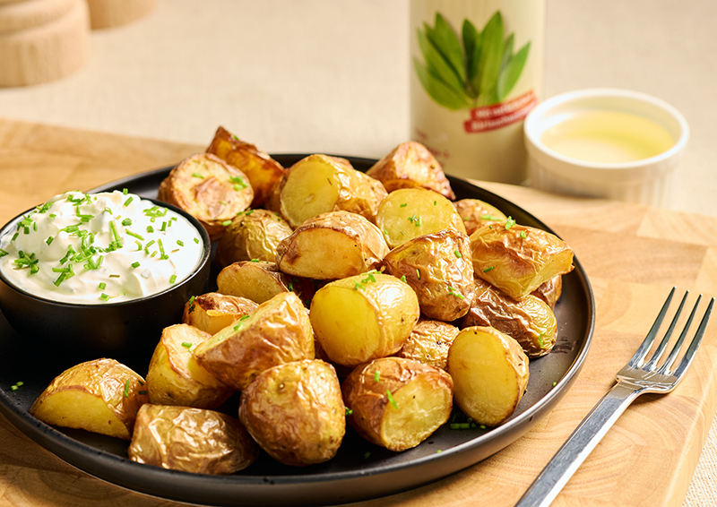 Teller mit knusprigen Ofenkartoffeln und Kräuterquark auf Holzbrett, serviert als einfache Beilage oder Mahlzeit
