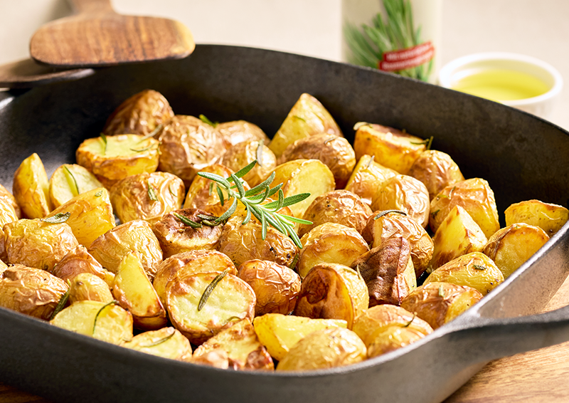 Goldbraun geröstete Kartoffelstücke mit Rosmarin in einer schwarzen Pfanne, appetitlich serviert zum Anrichten