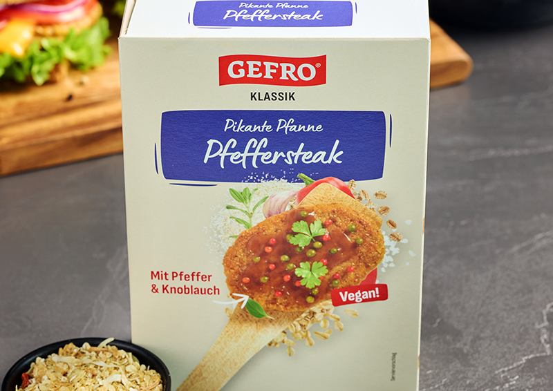 Verpackung von Gefro Klassik Pikante Pfanne Pfeffersteak, vegan, mit Pfeffer und Knoblauch auf grauem Hintergrund