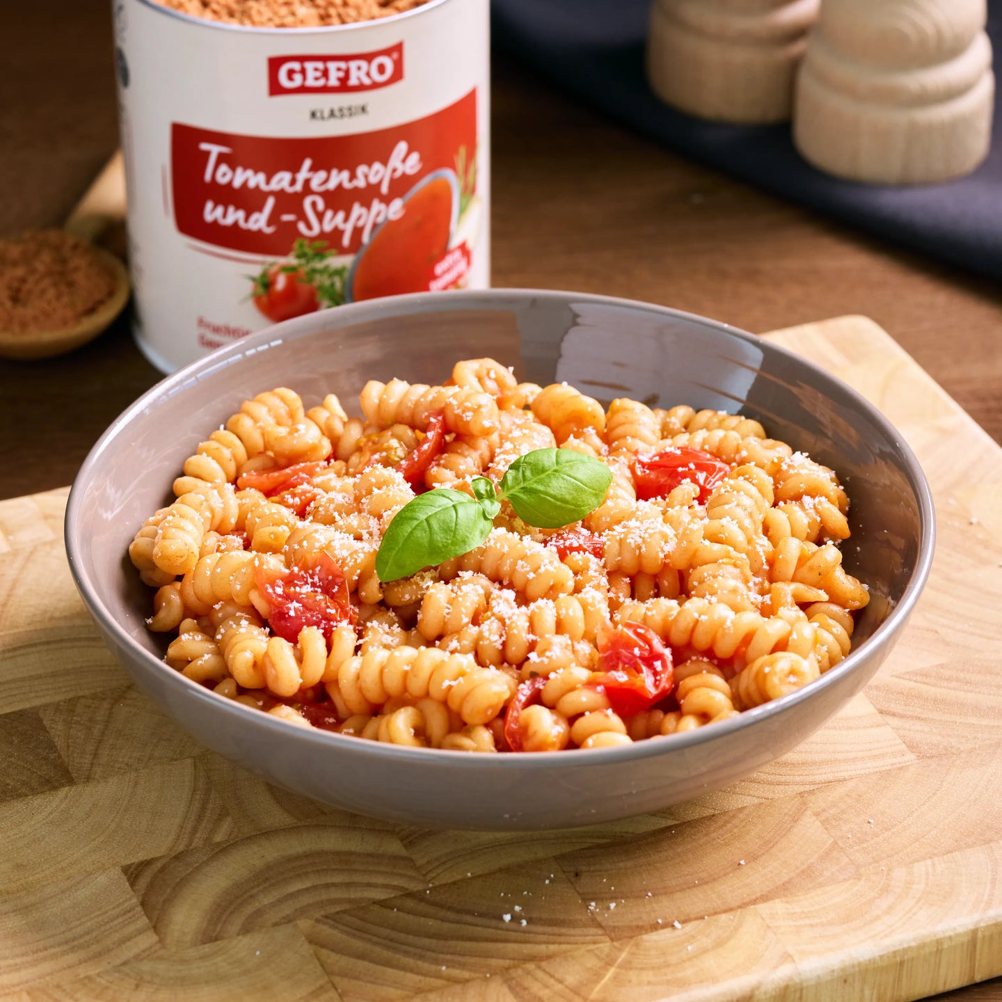 Schüssel mit Fusilli in Tomatensoße, garniert mit Parmesan und Basilikum, daneben Dose Tomatensuppe von Gefro