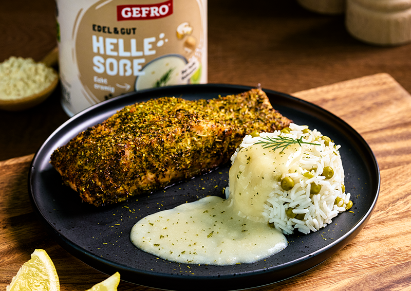 Gewürztes Fleischfilet mit Reis, Erbsen und heller Soße auf schwarzem Teller, dazu GEFRO Helle Soße im Hintergrund