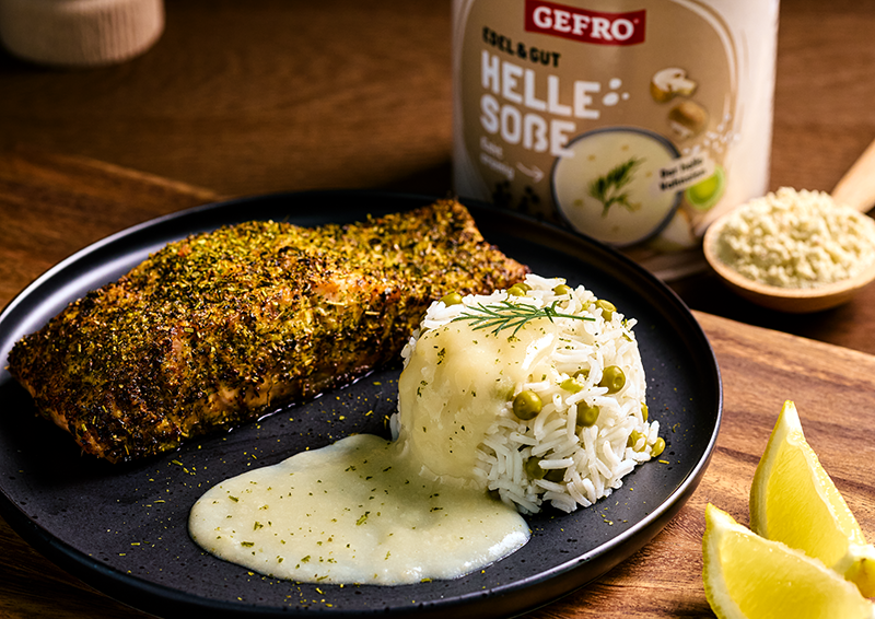 Gewürztes Lachsfilet mit Reis, heller Soße und Zitronenspalten auf schwarzem Teller, daneben GEFRO Helle Soße￼