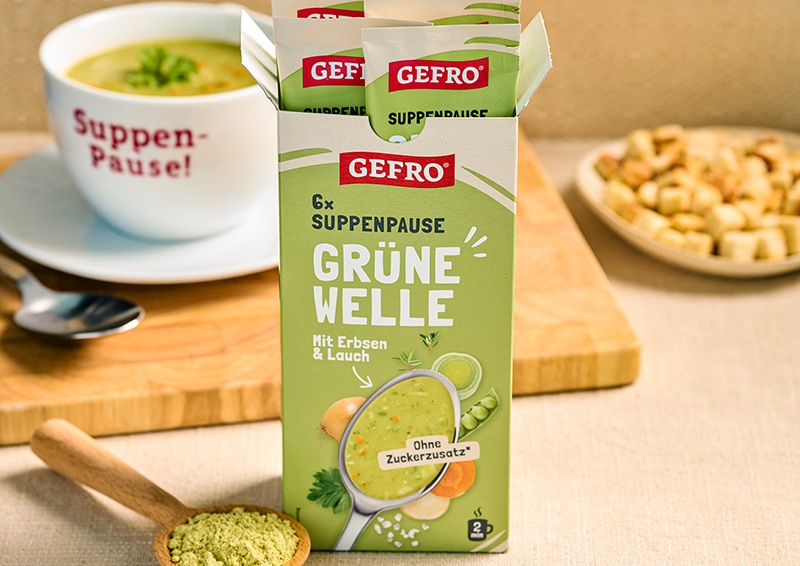 GEFRO Suppenpause Grüne Welle mit Erbsen und Lauch in geöffneter Packung, daneben Tasse Suppe und Croutons