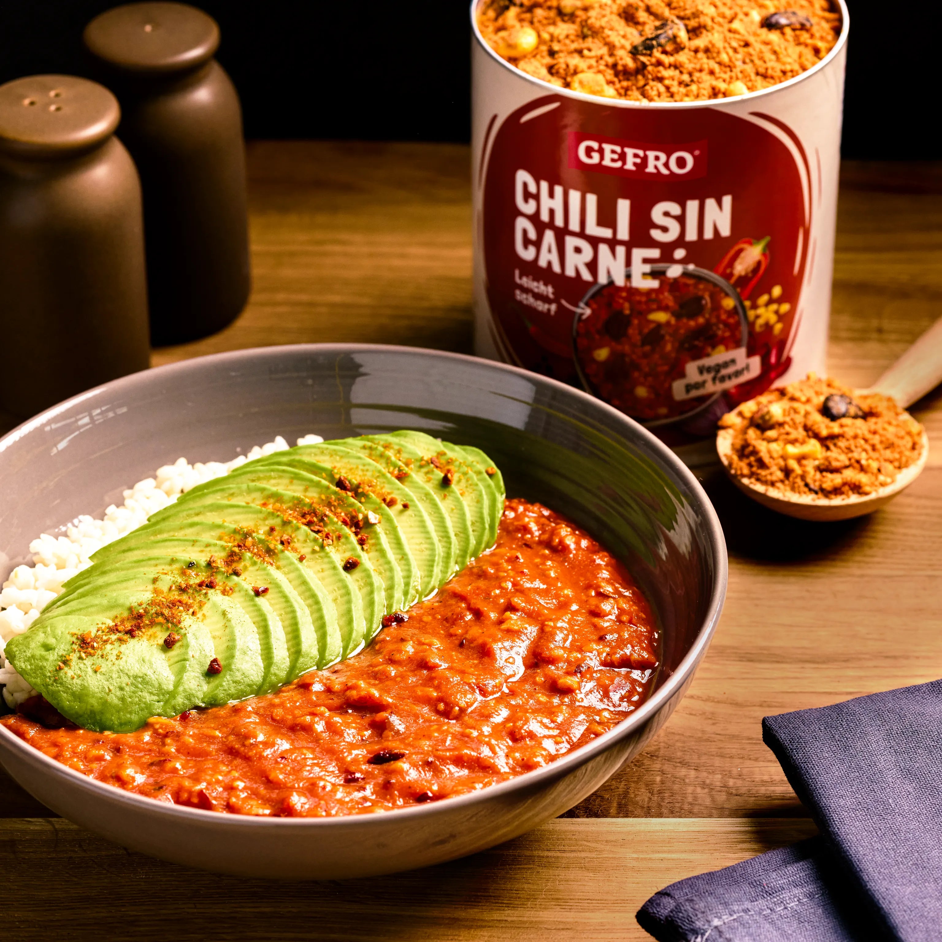 Schale mit Chili sin Carne, Reis und Avocadoscheiben; daneben Dose und Löffel mit Gewürzmischung von Gefro