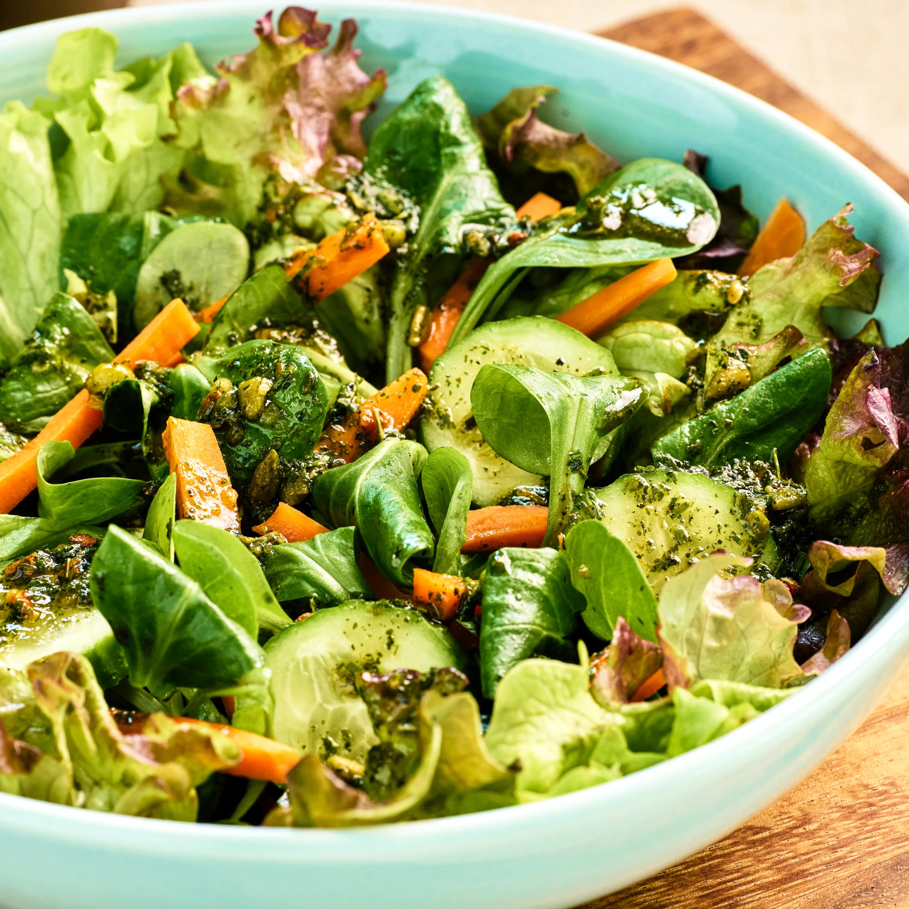 Schüssel mit frischem gemischtem Salat aus Blattsalat, Gurke und Karotten mit grünem Dressing