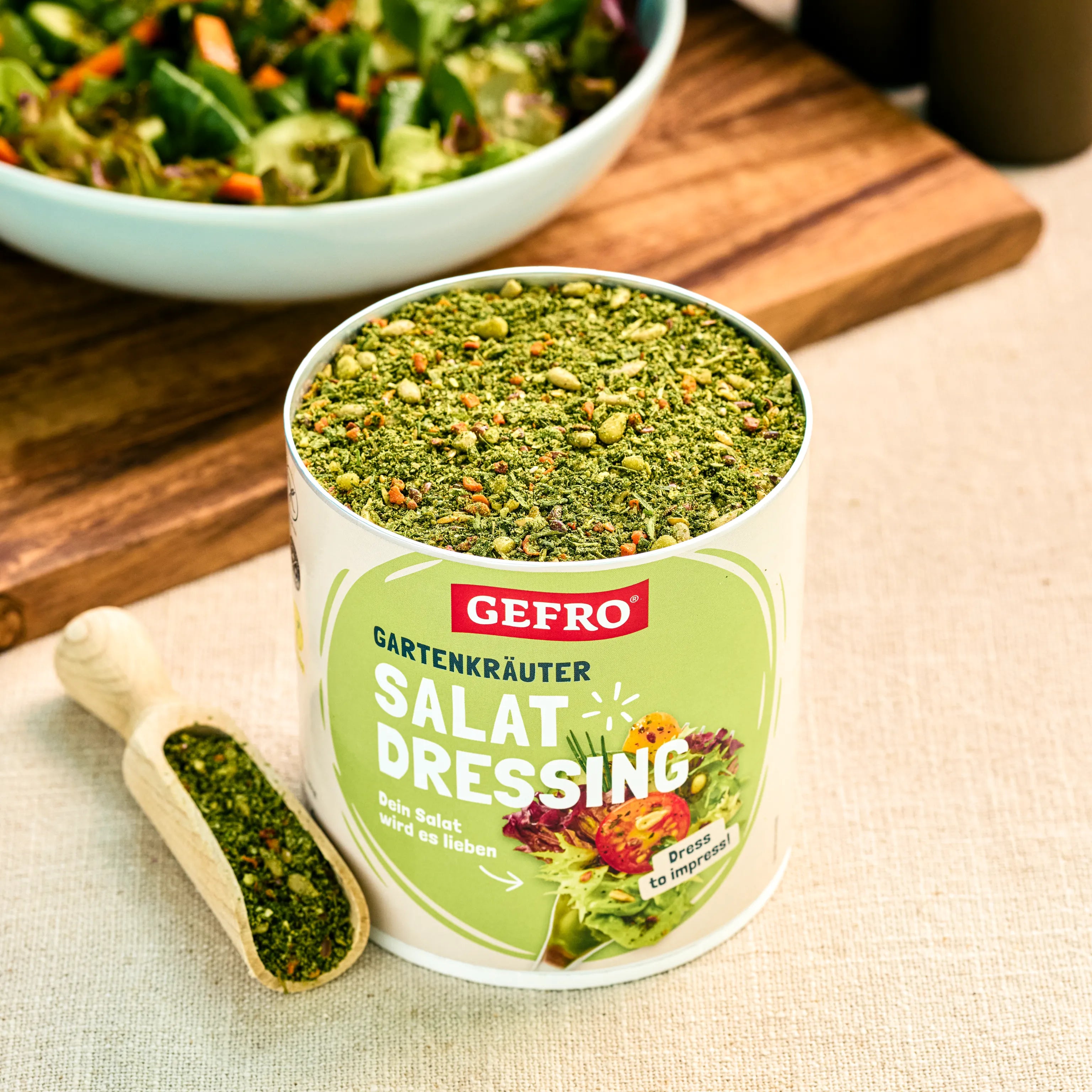 Offene Dose GEFRO Gartenkräuter Salat Dressing mit Kräutermischung, daneben Holzschaufel und Salat im Hintergrund