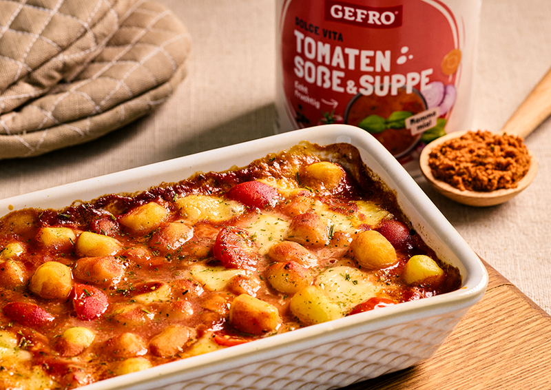Auflauf mit Gnocchi, Tomatensauce und Käse in weißer Form, daneben Verpackung von GEFRO Tomaten Soße & Suppe