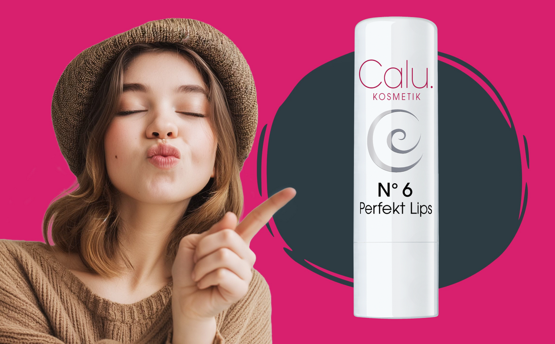 Junge Frau mit Hut und geschlossenen Augen macht einen Kussmund und zeigt mit dem Finger auf einen weißen Lippenpflegestift „Calu Kosmetik N°6 Perfekt Lips“ vor pinkem Hintergrund.