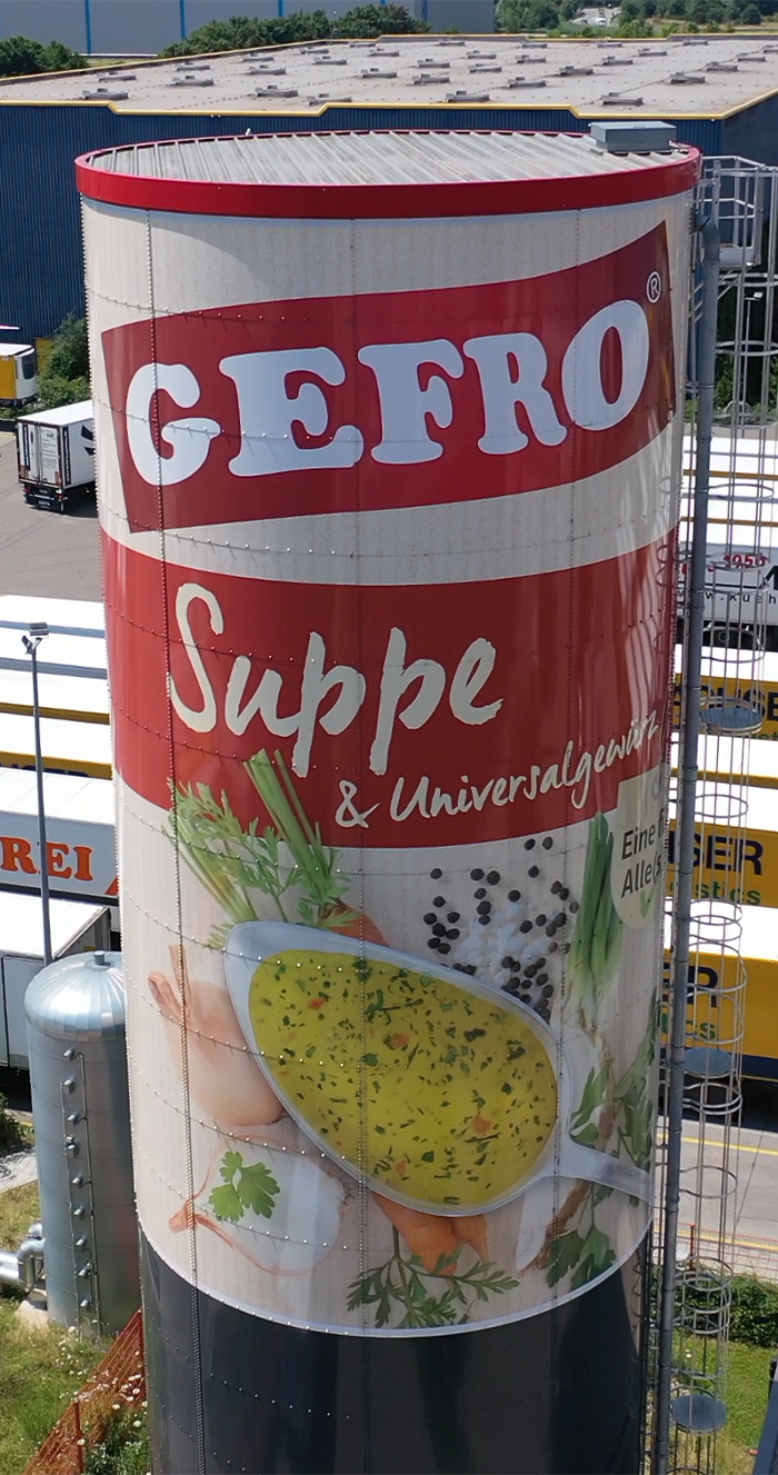 Großer Silotank mit Werbung für Gefro Suppe und Universalgewürz, gestaltet wie eine Suppendose mit Zutaten.