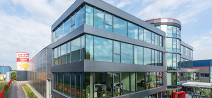Modernes Büro- und Firmengebäude mit großer Glasfassade, aufgenommen aus schräger Außenansicht bei Tageslicht