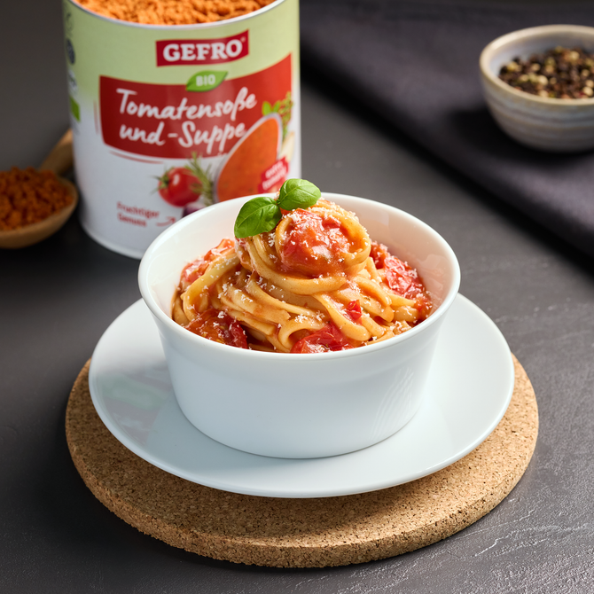 Schale mit Pasta in Tomatensoße und Basilikum, daneben GEFRO Bio Tomatensoße und -Suppe im geöffneten Behälter