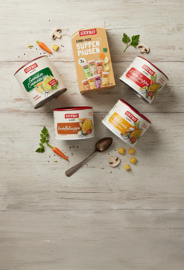 GEFRO Suppen-Pausen Kombi-Pack mit vier Suppenbechern, Löffel und Gemüse dekorativ auf hellem Holztisch verteilt