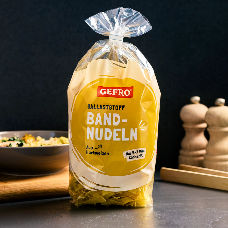 Packung GEFRO Ballaststoff-Bandnudeln aus Hartweizen auf Küchentisch, mit Schale und Gewürzmühlen im Hintergrund
