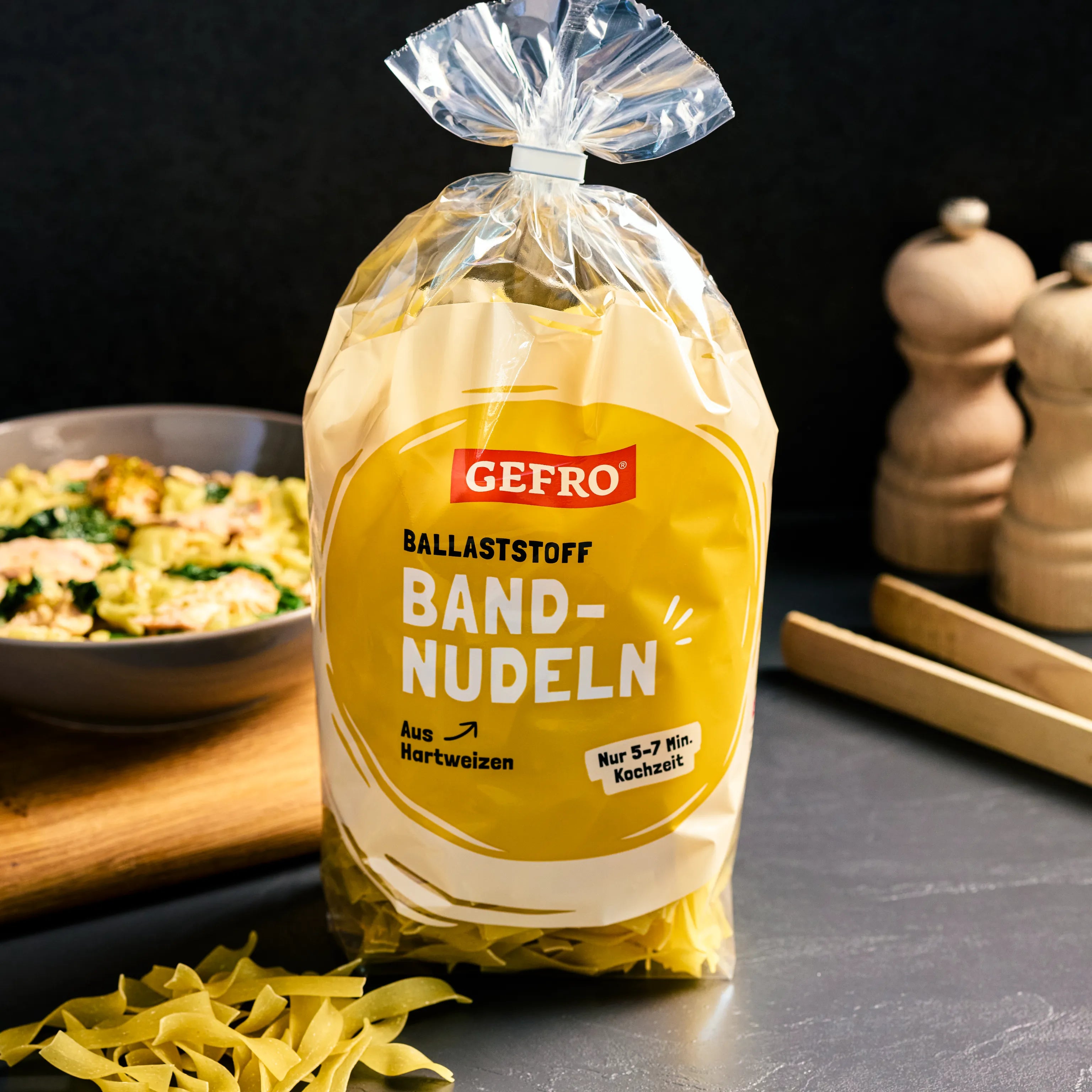 Verpackung mit GEFRO Ballaststoff-Bandnudeln aus Hartweizen, auf Küchentisch neben Teller mit Pasta präsentiert