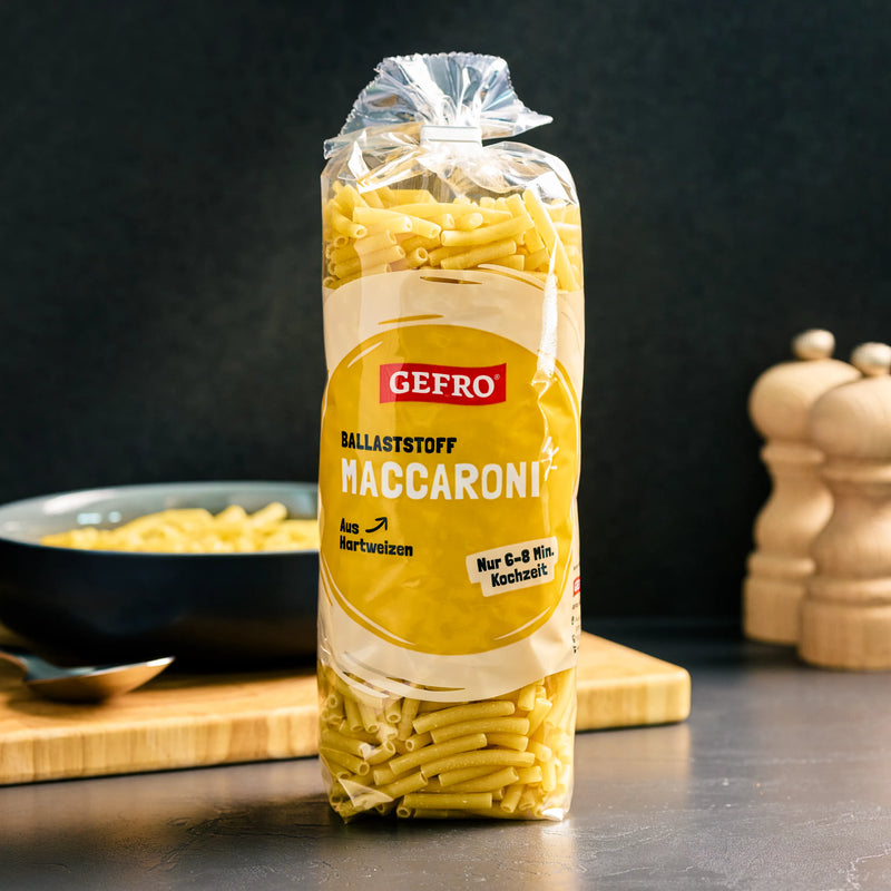 Packung GEFRO Ballaststoff-Maccaroni aus Hartweizen auf einer Küchenfläche, mit Schüssel und Gewürzmühlen im Hintergrund