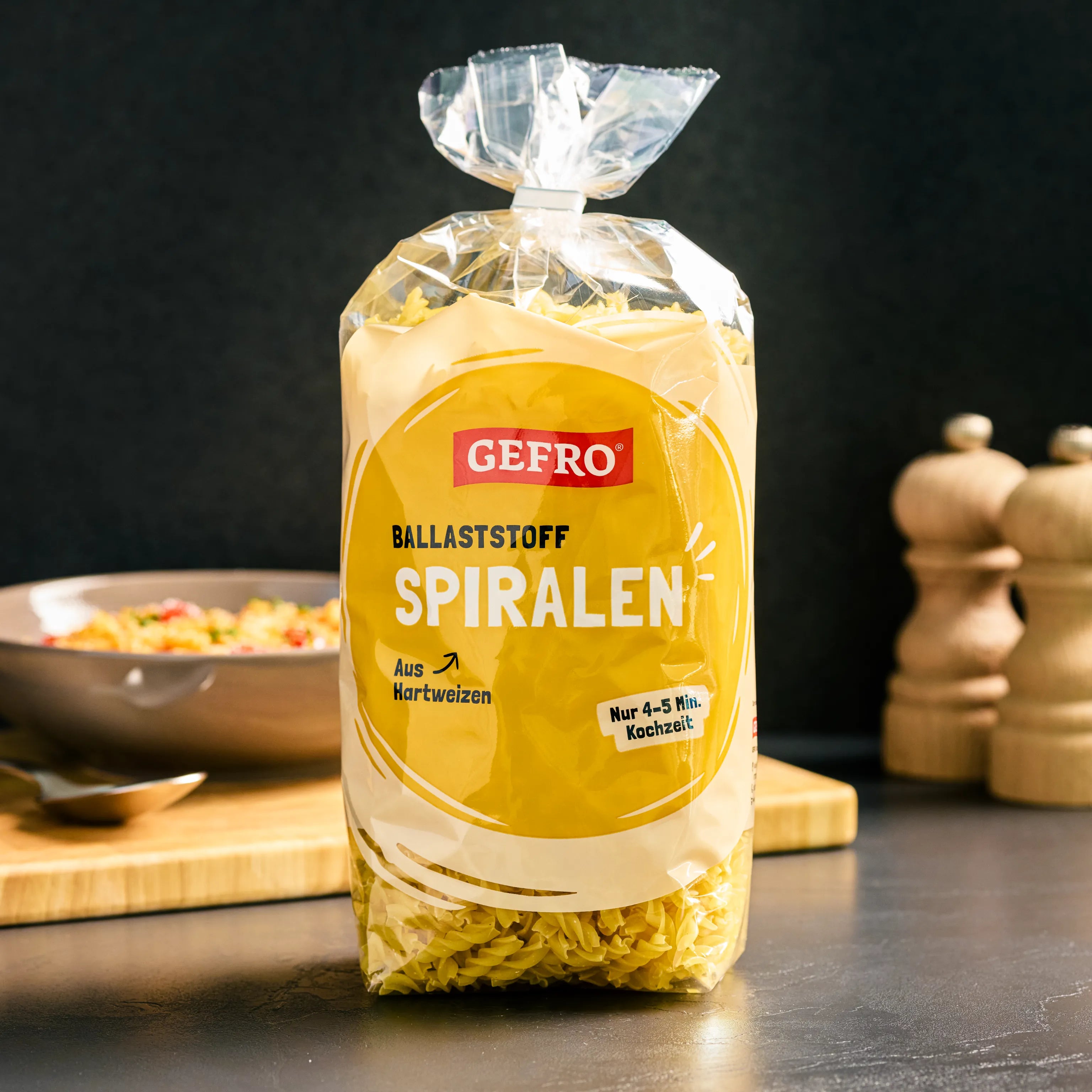 Verpackung GEFRO Ballaststoff-Spiralen aus Hartweizen auf Küchentisch, im Hintergrund Teller und Gewürzmühlen