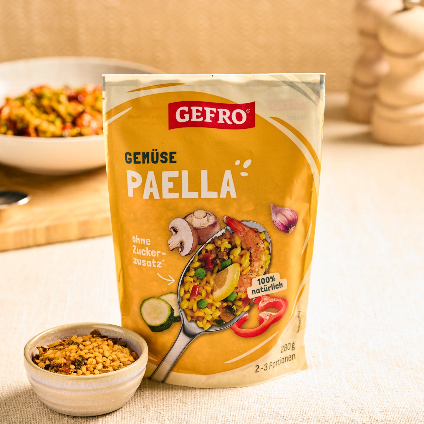 GEFRO Gemüse Paella im Beutel auf Küchentisch, davor eine Schale mit Mischung, im Hintergrund ein Teller Paella.
