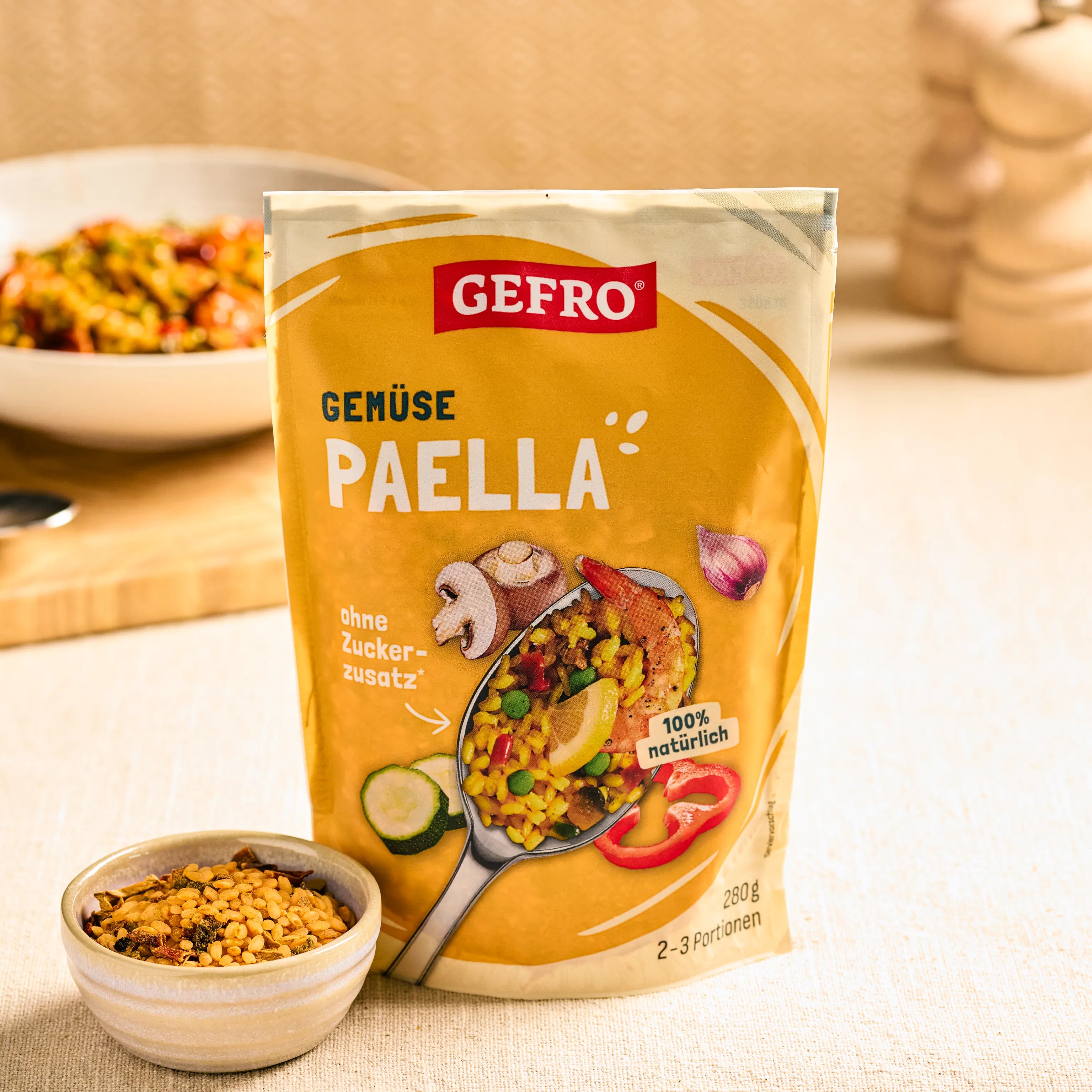 GEFRO Gemüse Paella im Beutel auf Küchentisch, davor eine Schale mit Mischung, im Hintergrund ein Teller Paella.