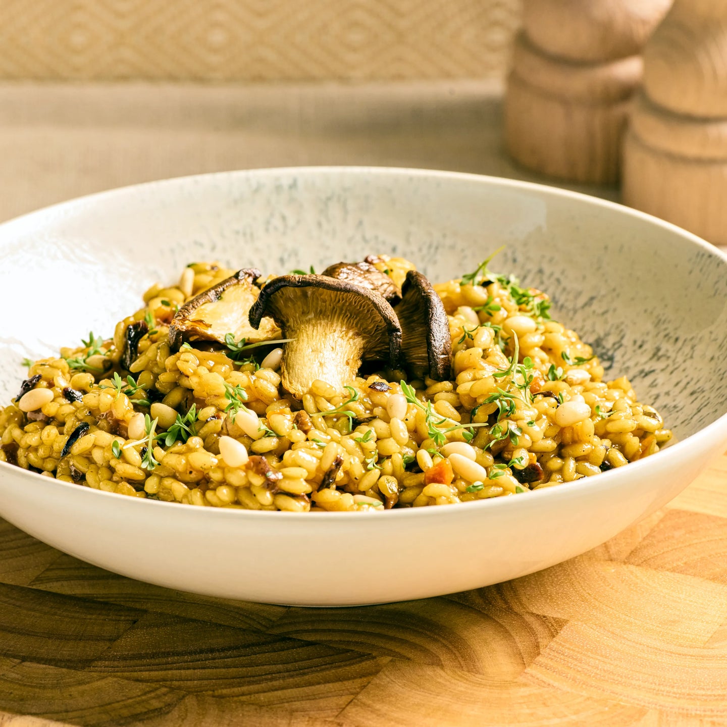 Cremiges Risotto mit gebratenen Pilzen, Kräutern und Pinienkernen in einer hellen, tiefen Schale serviert